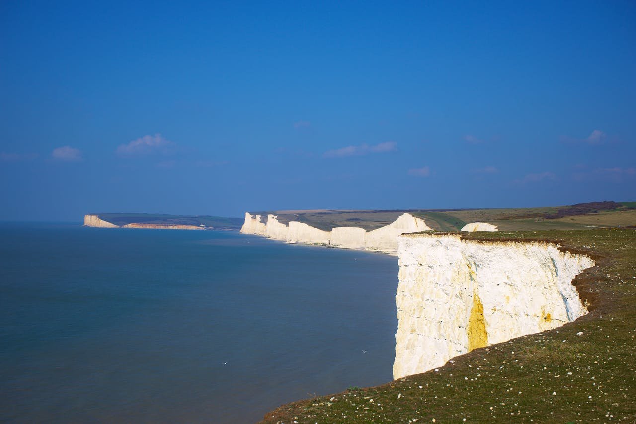 Serene view of the iconic Seven Sisters cliffs against a blue sky in Eastbourne, UK.